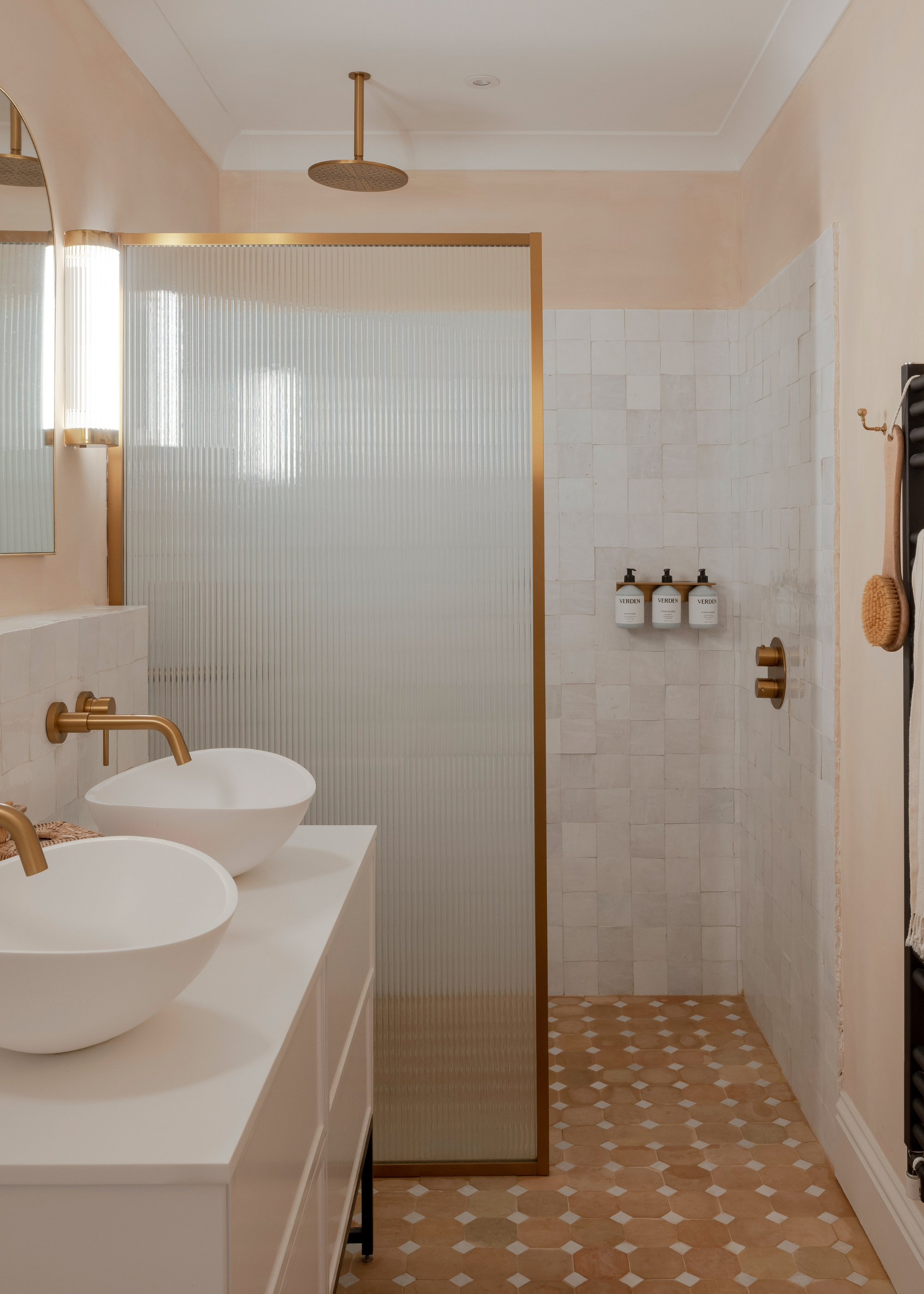 a shower room with rustic, terracotta tiles and a double sink as well as a shower are