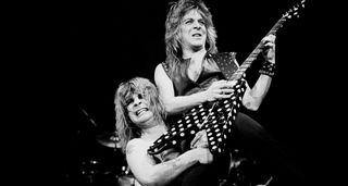 Ozzy Osbourne hoists Randy Rhoads aloft onstage as Rhoads solos on his polka-dotted Sandoval V-style electric guitar.