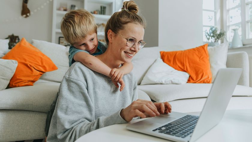 Woman on laptop with her son hugging her from behind