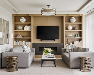 Living room with two neutral sofas facing, coffee table, wall mounted TV and surrounding shelves