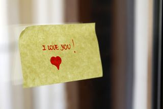 A yellow sticky note with the words 'I LOVE YOU!' written in red with a red heart.