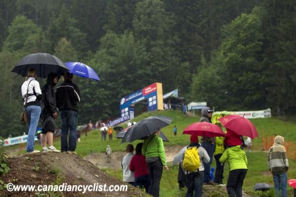 Spectators stand in the rain