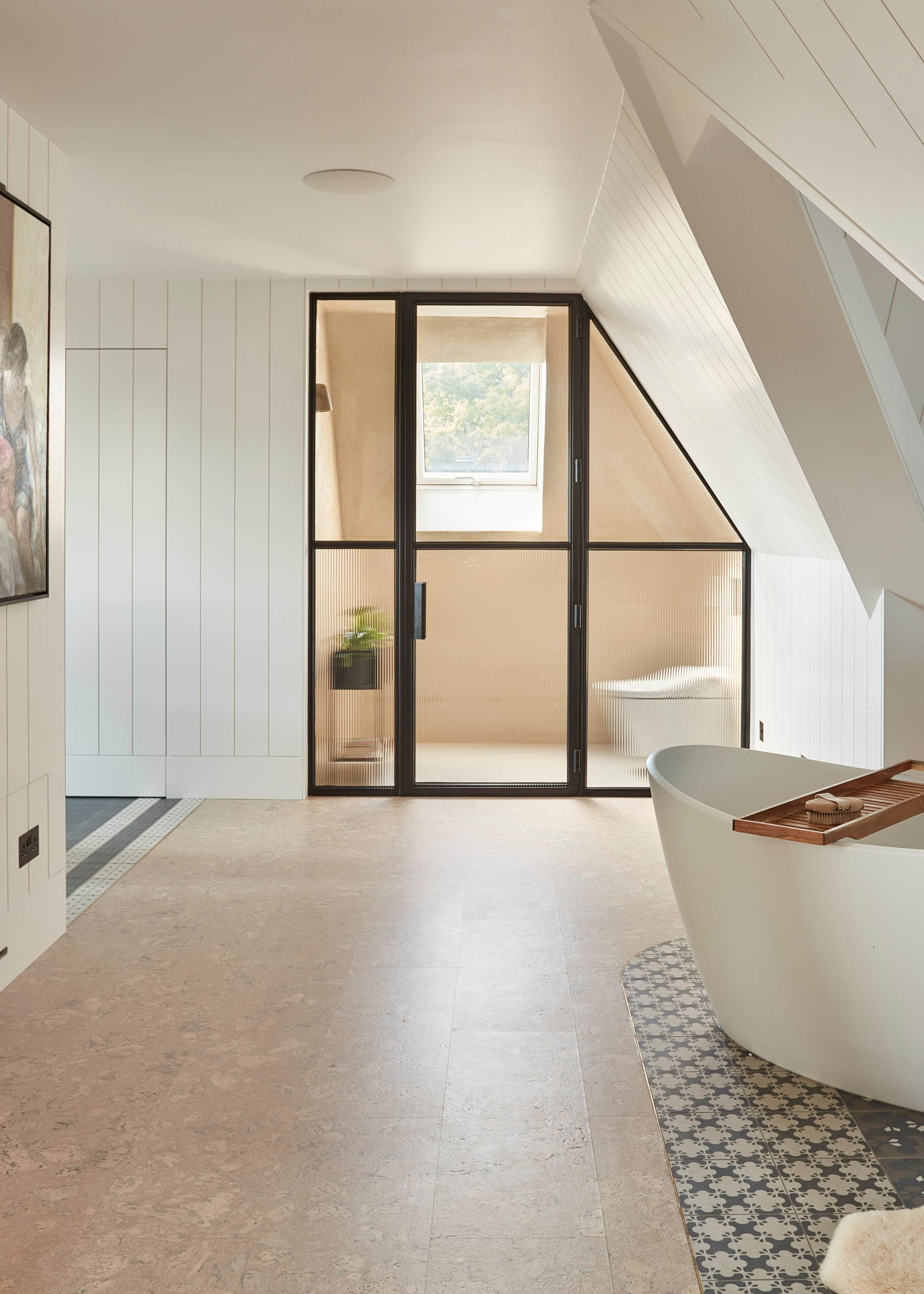 a large bathroom with cork flooring and a freestanding tub and a glass-fronted toilet area