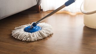 Person using a white mop to clean hardwood floors.
