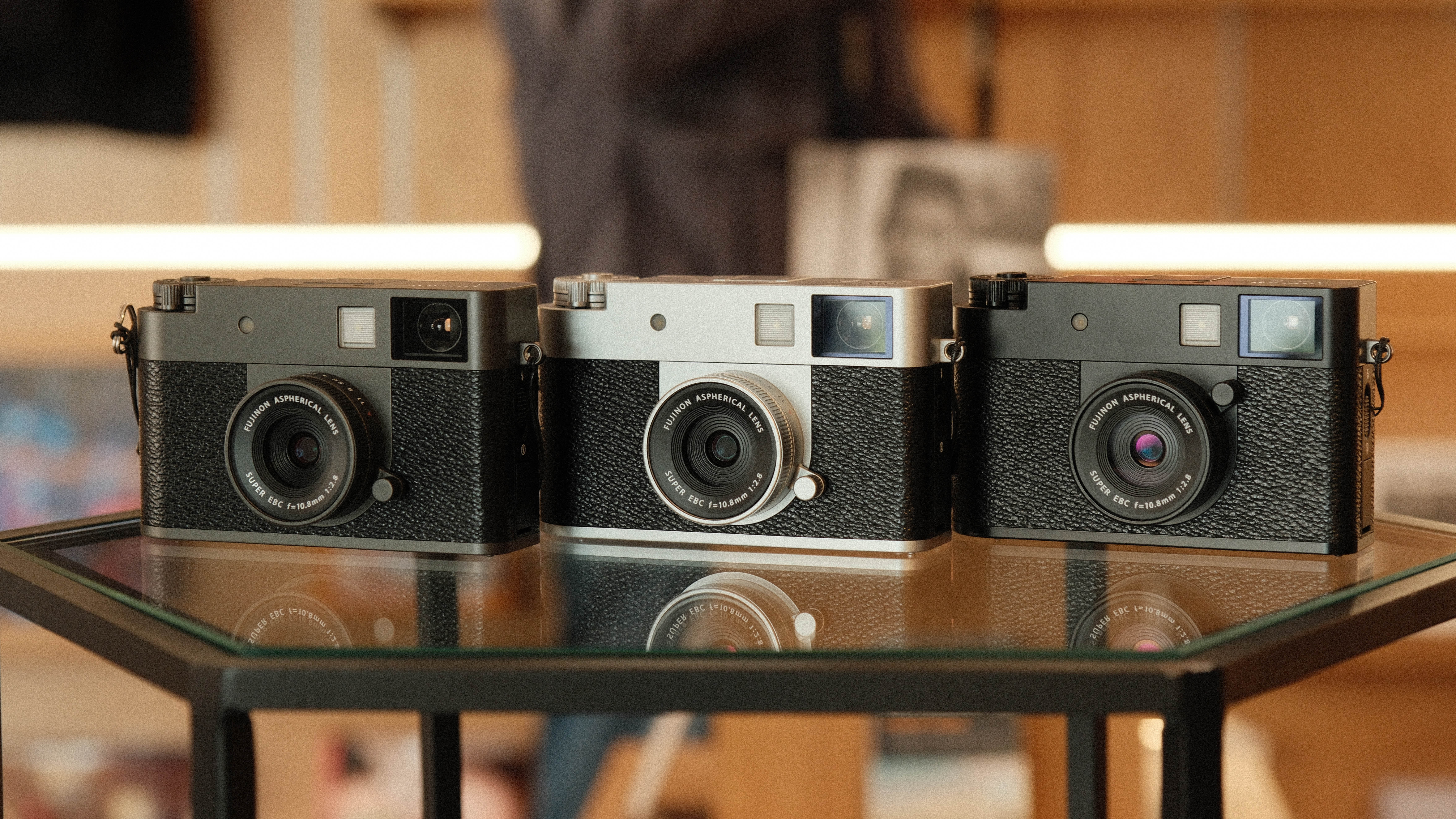 Fujifilm X Half camera in three colors next to one another on a glass table