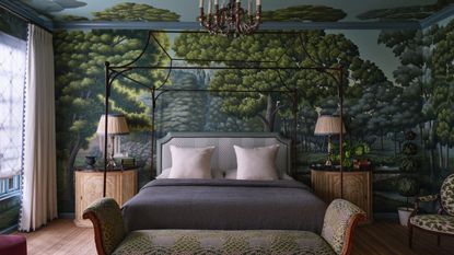bedroom with wall mural, four poster bed, two large side tables with lamps, a bench at the foot of the bed