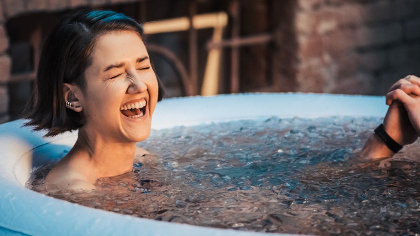 Woman laughing in an ice bath outdoors during cold plunge