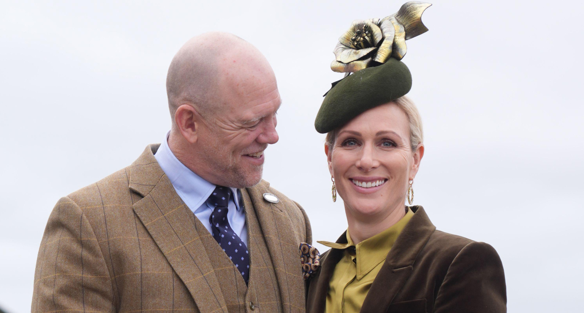 Mike Tindall in a brown suit smiling at Zara Tindall, dressed in a green suit and hat