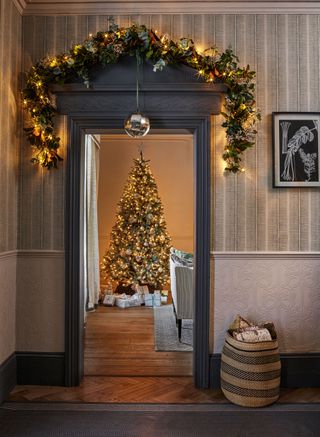 a doorway decorated for Christmas with a Christmas tree in the next room