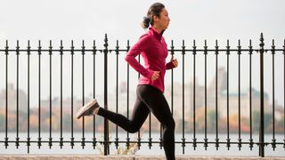 Woman running next to fence
