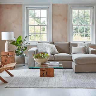 A grey chaise sofa in a living room with bare plaster walls