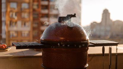 A Kamado Joe II grilling with the lid closed on a rooftop