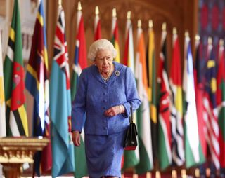Queen Elizabeth II walks past Commonwealth flags in St George's Hall at Windsor Castle