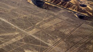Aerial photo of Nazca lines in Peru. These geoglyphs contain a lot of straight lines, geometric shapes, and trapezoids.