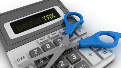 A pair of scissors sits open on top of a calculator that displays the word tax.