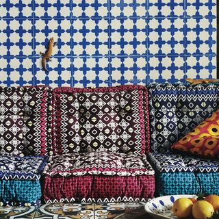 designed floor cushions blue designed tile wall and fruits in plate