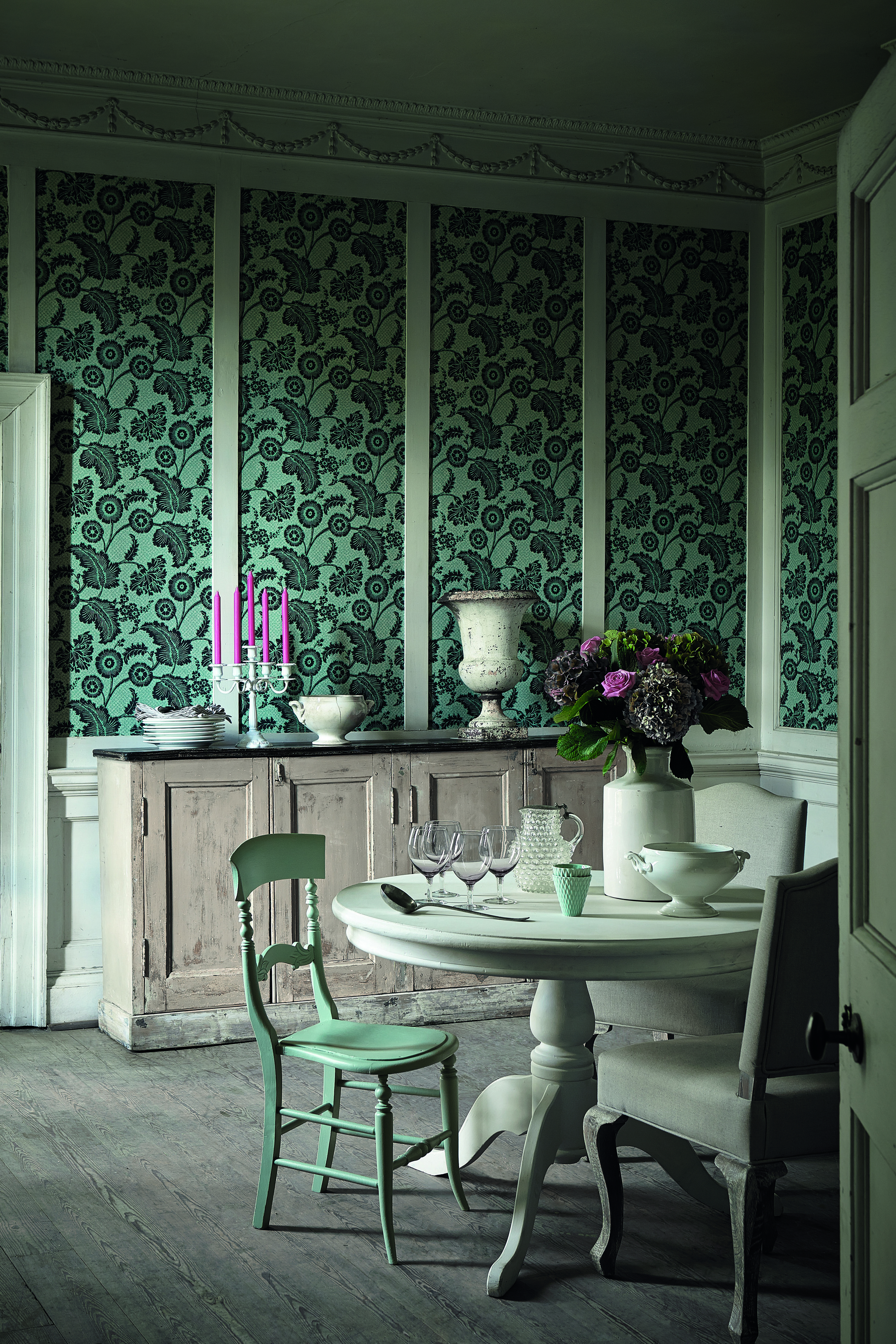 classic dining room with wallpaper between panels, white table, painted chairs, antique sideboard