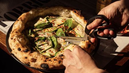 A photo of a pizza being cut with scissors. 