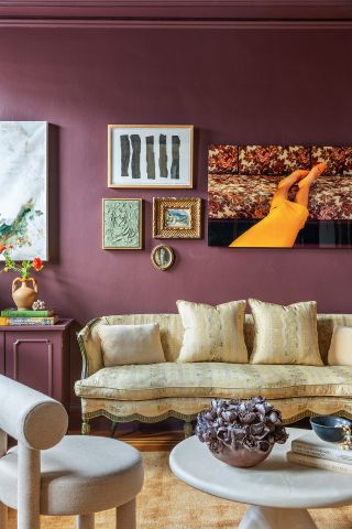 living room with deep purple walls, artwork, a yellow sofa, and white coffee table