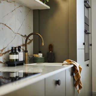 Magnet kitchen with brass tap and green cabinets