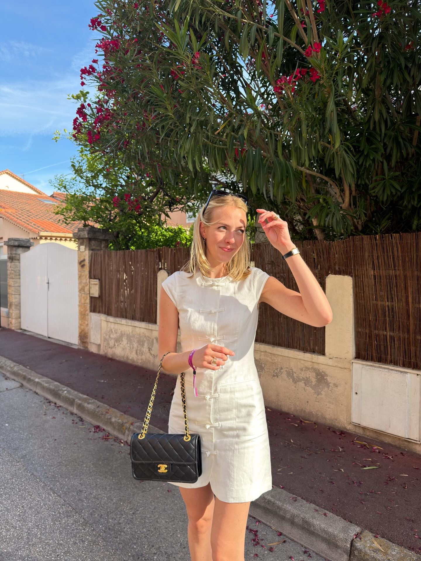 Woman wears the white Aligne dress, carries black Chanel bag