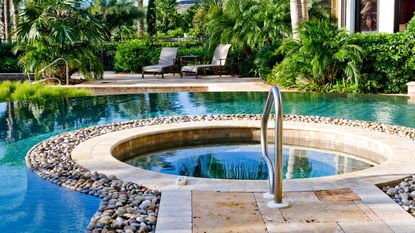 A hot tub in laid beside a pool