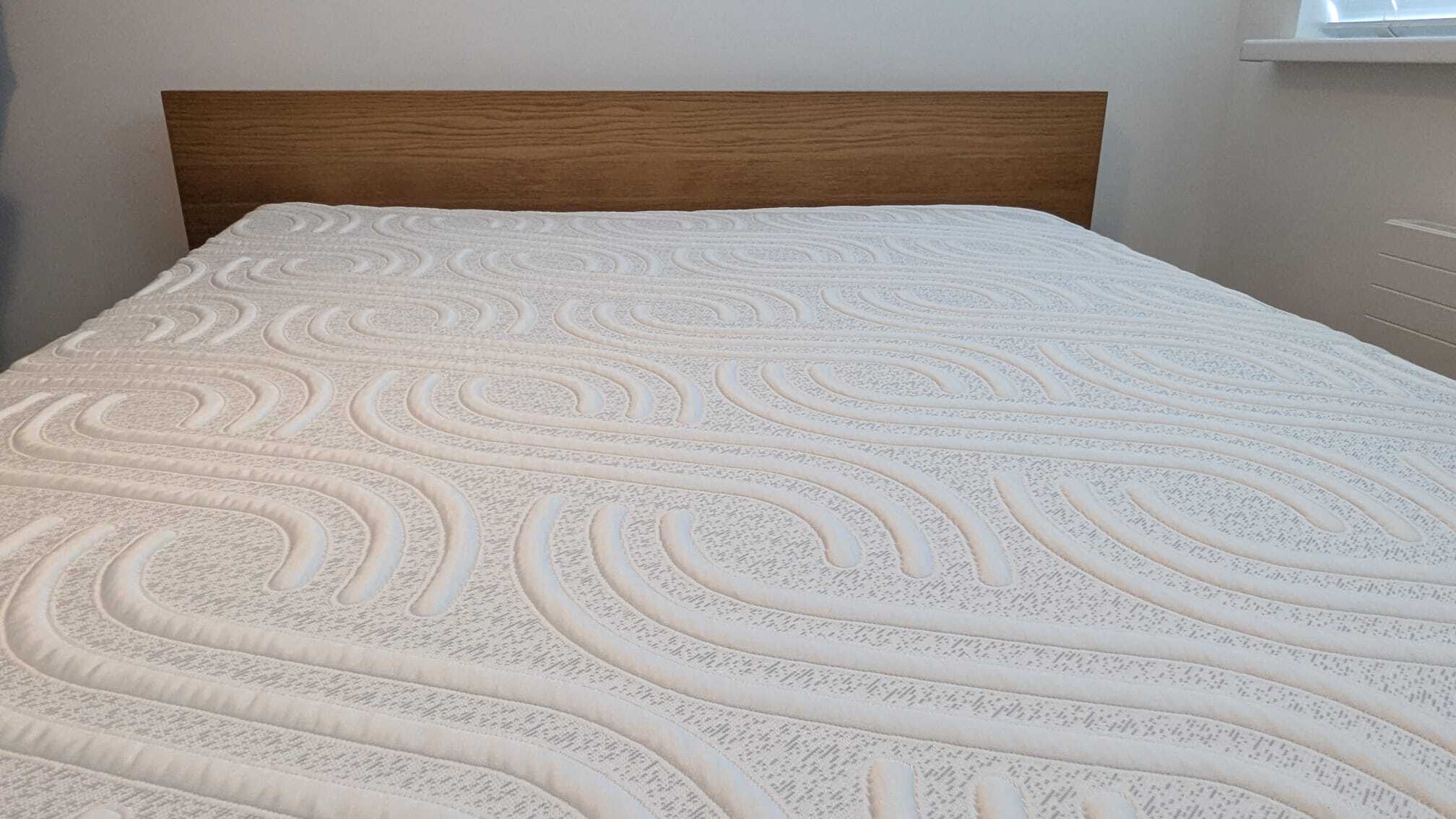 The image shows a white mattress on a wooden bed frame following a deep clean to remove dust mites