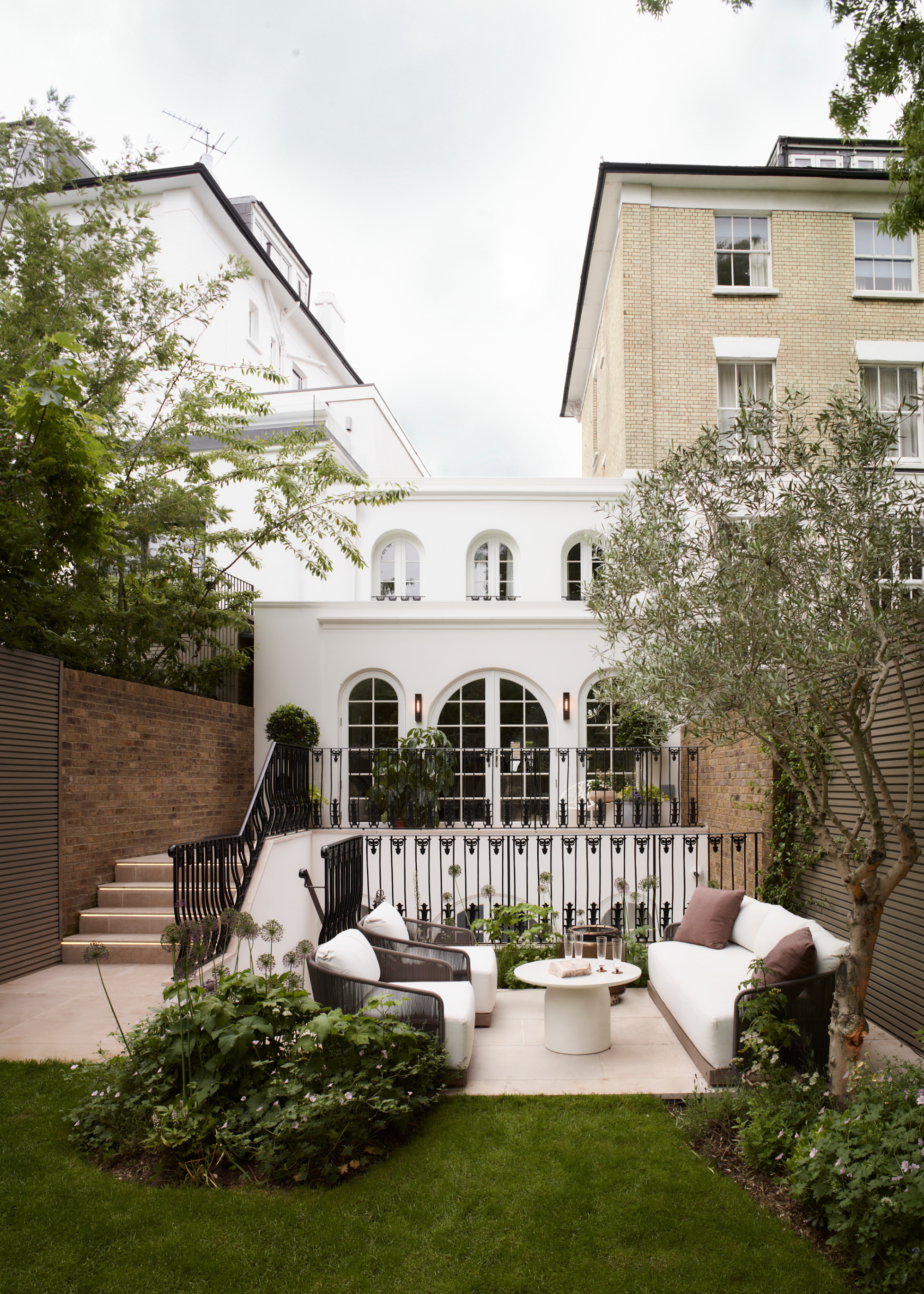 An outdoor garden with a living room and patches of plants around it
