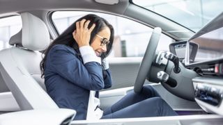 An angry woman in a car covering her ears
