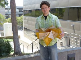 NASA engineer Brian Trease holds the prototype of the origami-inspired solar panel arrays.