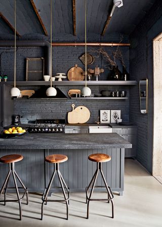 a dark kitchen with a trio of white pendant lights