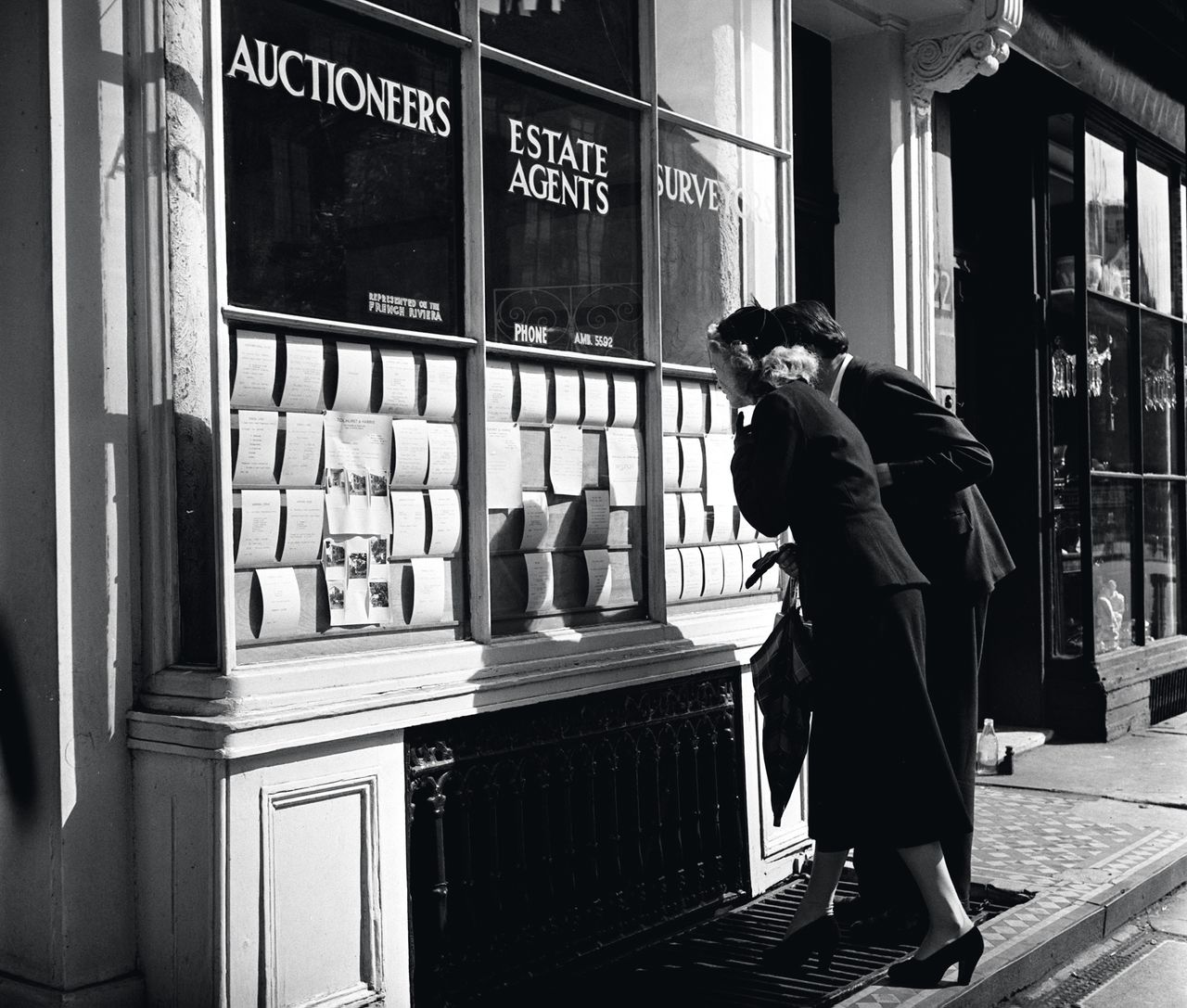 England, 1950, A couple are pictured house hunting as they look at the cards on display in an Estate Agents