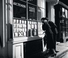 England, 1950, A couple are pictured house hunting as they look at the cards on display in an Estate Agents