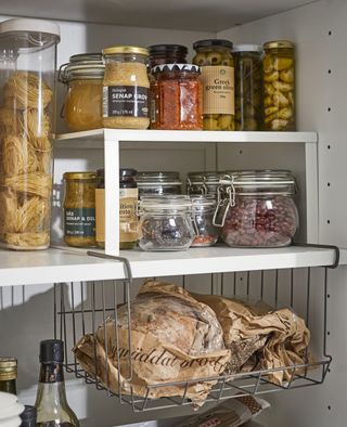 Ikea basket shelf insert used to double space in a kitchen cupboard with food containers