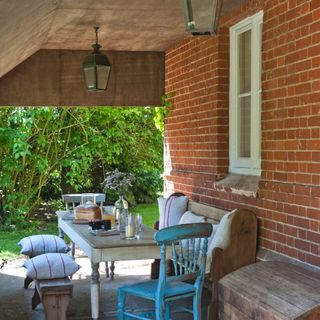 patio cover ideas, with wooden structure, vintage style table and bench seating, painted chairs, stripe cushions, lanterns