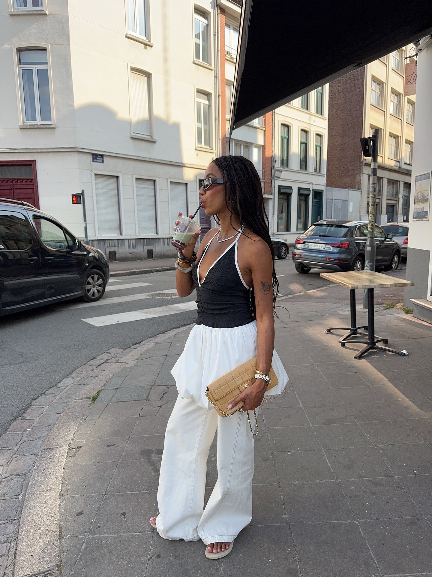 Fashion person Amaka Hamelijnck wears beige shoes, white denim jeans, a white bubble skirt and white and black halterncek top in a recent image from her Instagram.