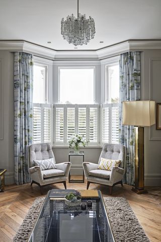 Living room bay window dressed with curtains and shutter
