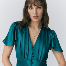 Model wearing a satin teal dress with a gold pendant necklance sold at Ghost