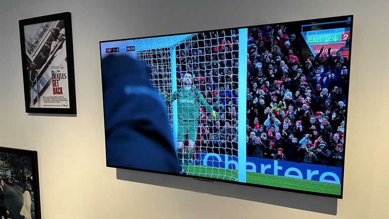 LG C2 mounted on wall, showing football on the screen