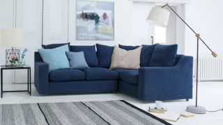 A navy blue corner sofa bed in a white living room