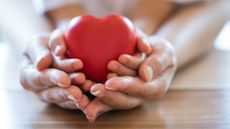 Adult and child hands holding red heart