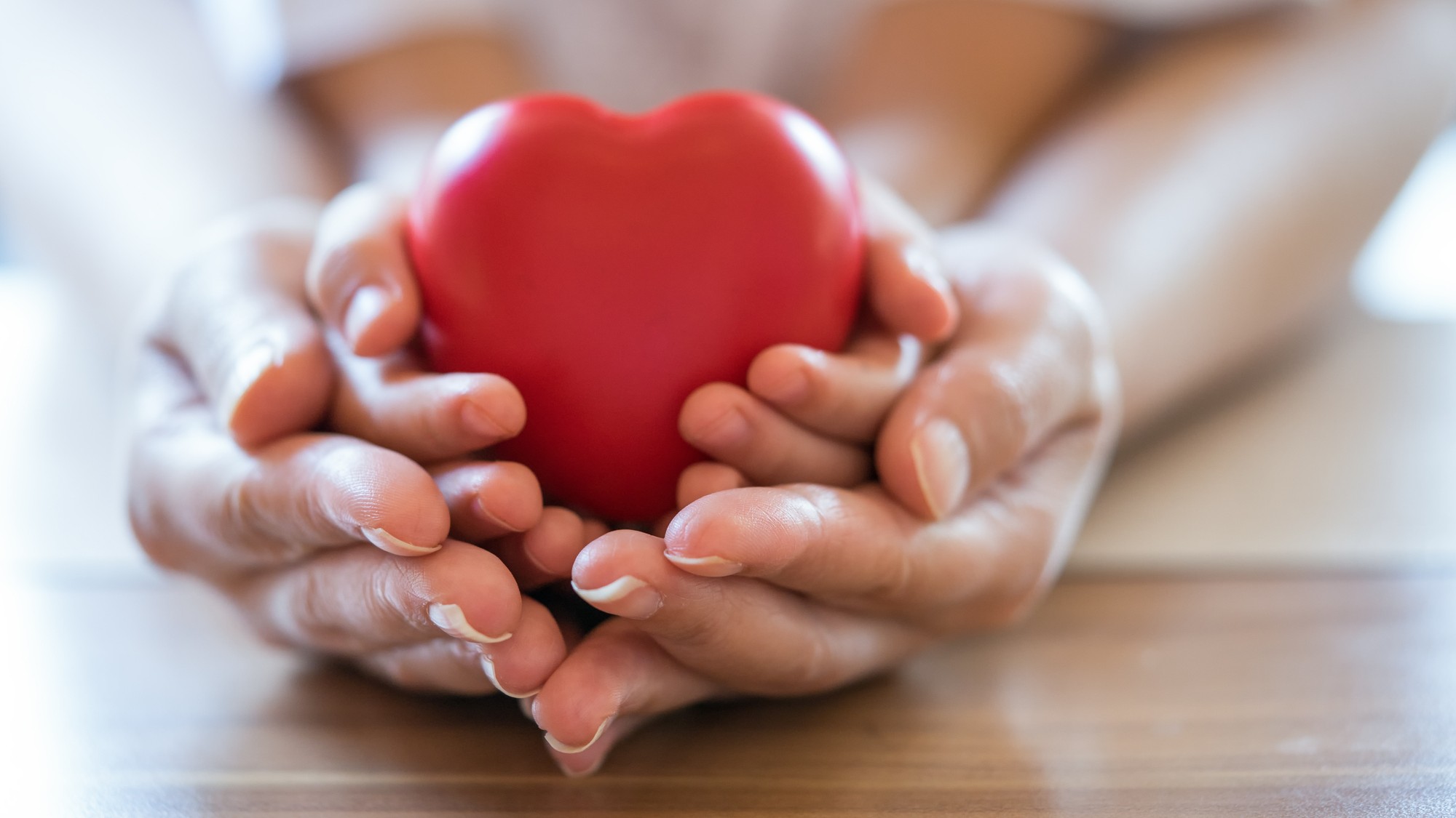 Adult and child hands holding red heart