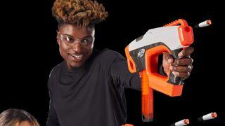A man aims and fires a Nerf Pro Sender blaster with a smile