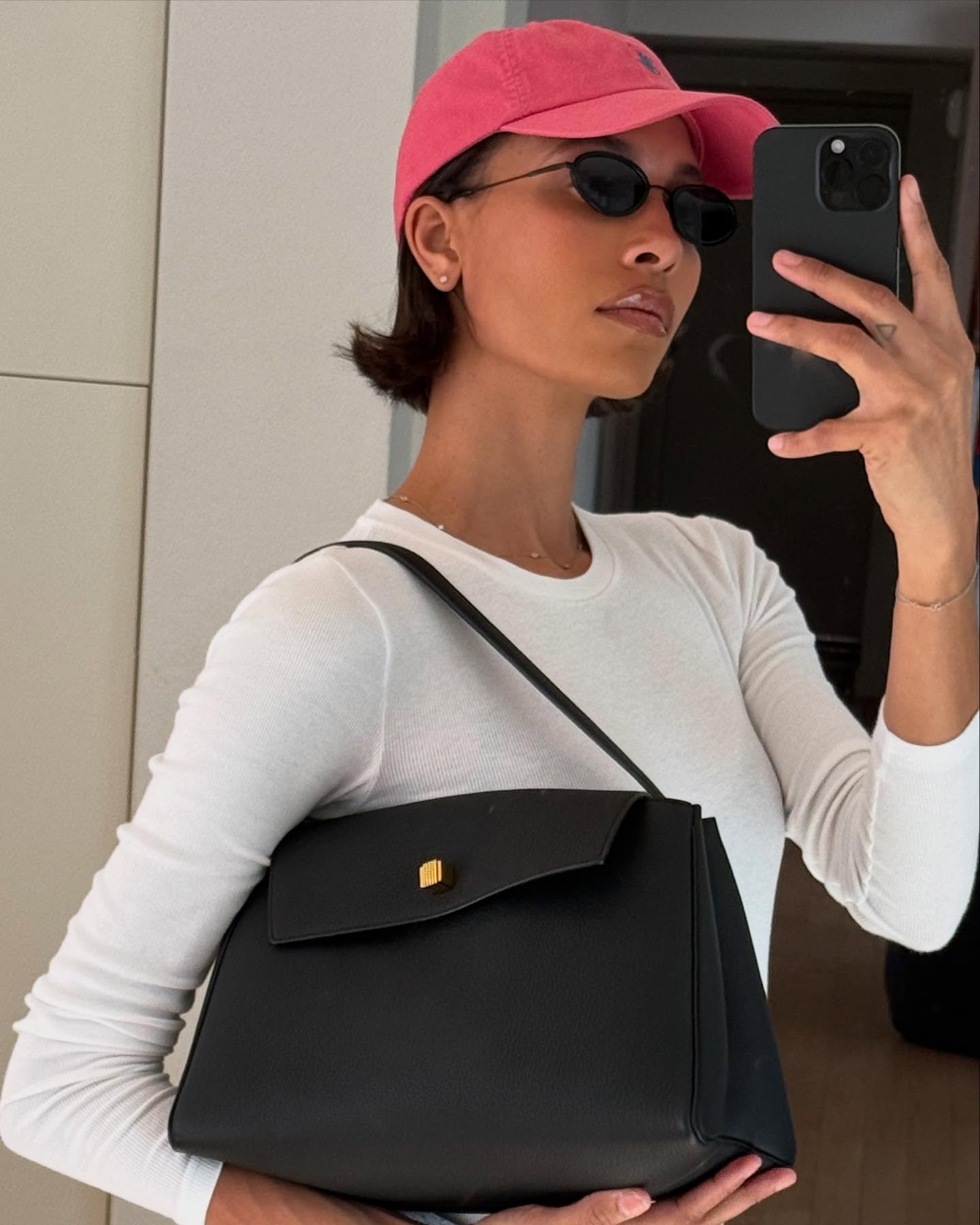A woman taking a mirror picture wearing sunglasses and a Ralph Lauren cap