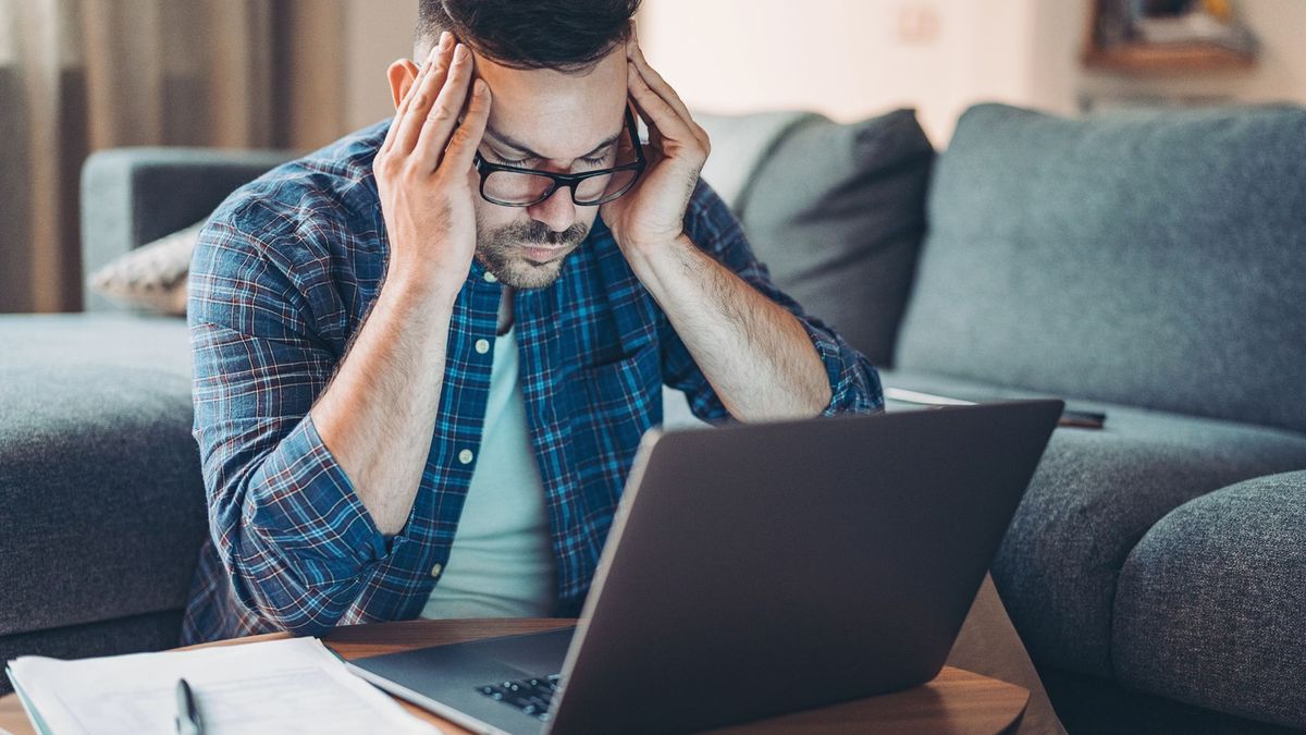 A tired or stressed man at home using a laptop