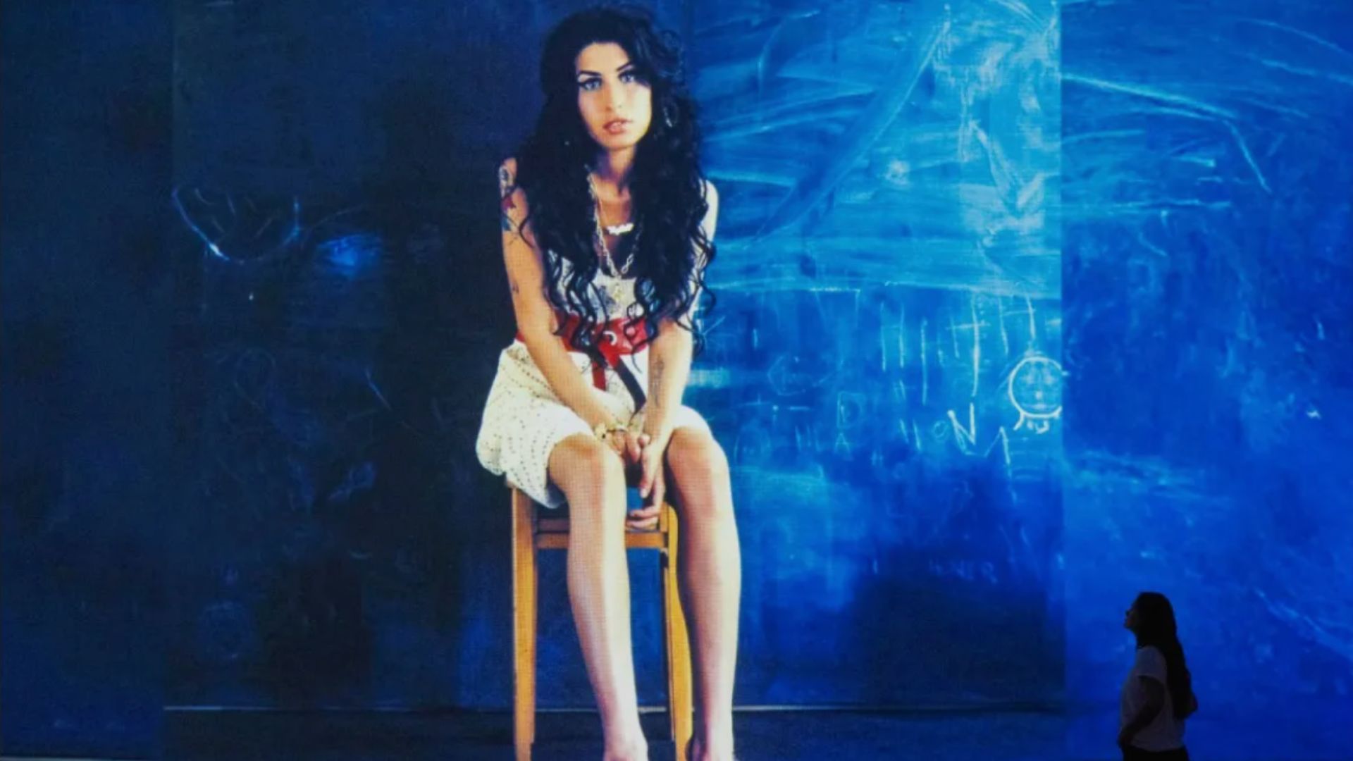 a famous portrait of amy winehouse projected onto the walls of the gallery with a woman looking at it