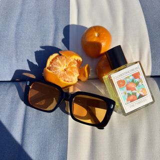 Clementine Dream Eau de Parfum next to clementines and a orange-and-black sunglasses.