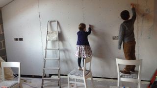children drawing on bare plasterboard