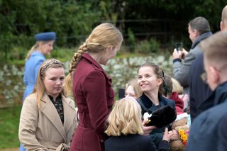 Princess Charlotte wearing a green plaid coat smiling and speaking with her cousins Mia Tindall and Savannah Phillips on Christmas