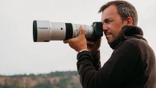 XF 500mm f/5.6 R LM OIS WR lens attached to a camera and held up to a person's face